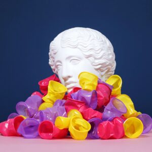 Plaster head buried in disposable plastic cups. Pollution concept