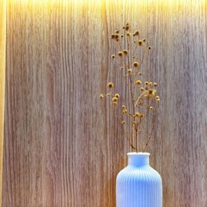 Dried flowers in an elegant white vase against a warm wooden background